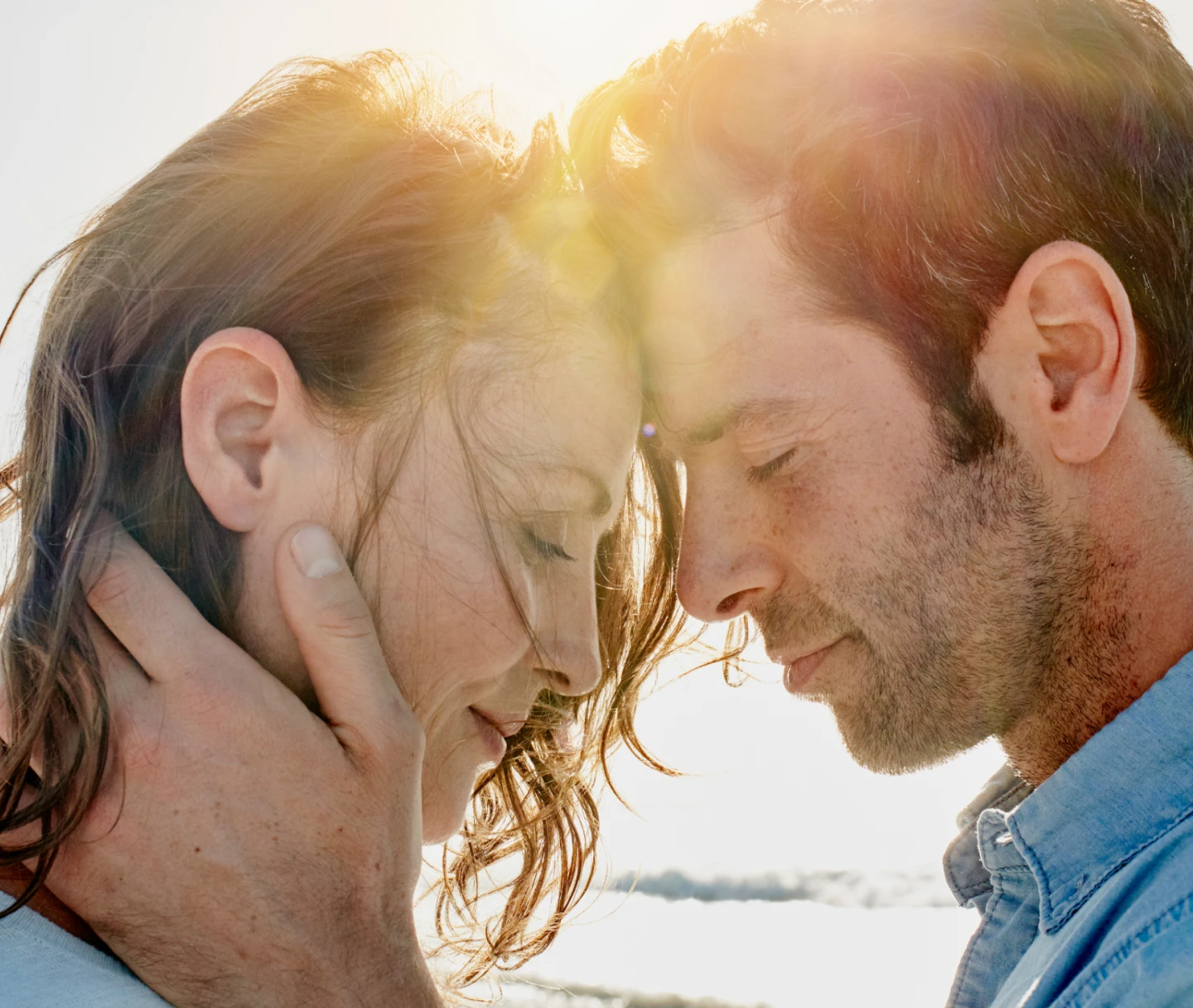 A man and woman lovingly put their heads together during a sunny day at the beach